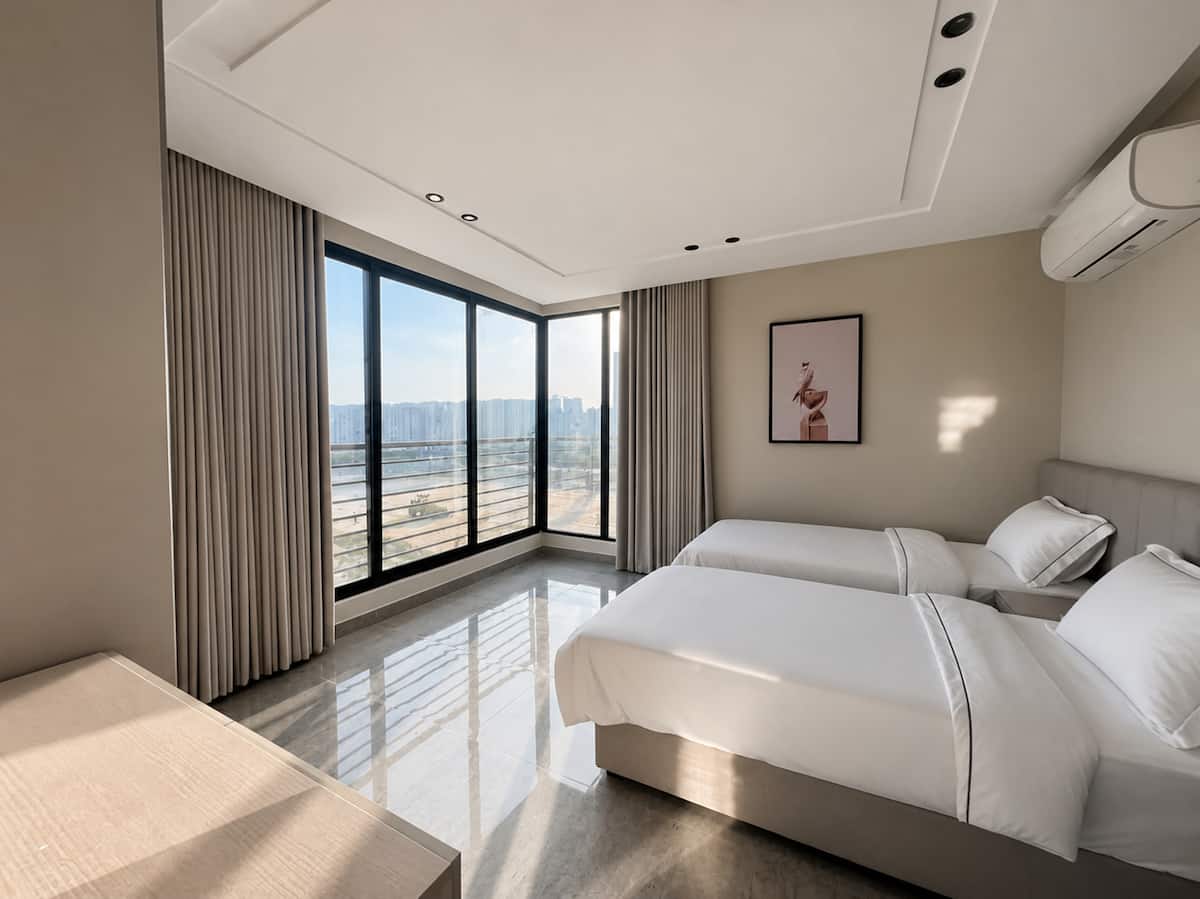 Twin bedroom with broad windows in the Rihab apartment